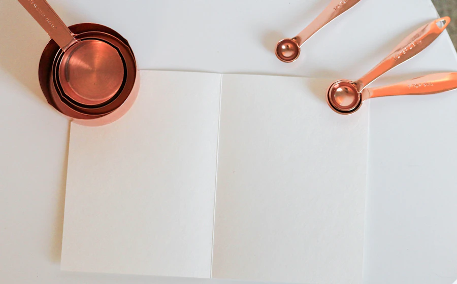 An open recipe notebook and measuring cups on a kitchen worktop